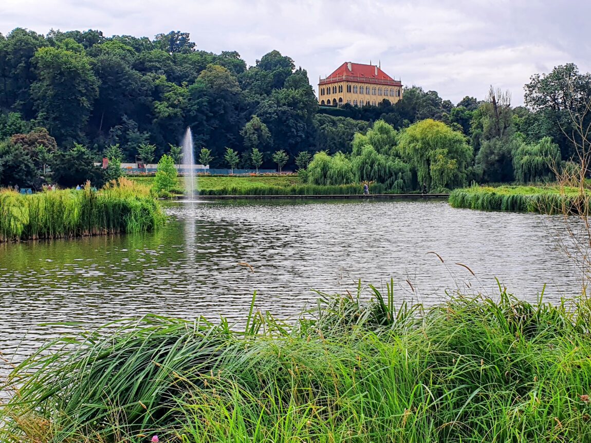 View of the pond and Governor's Summer House at Stromovka Park in Prague, on a partly cloudy day