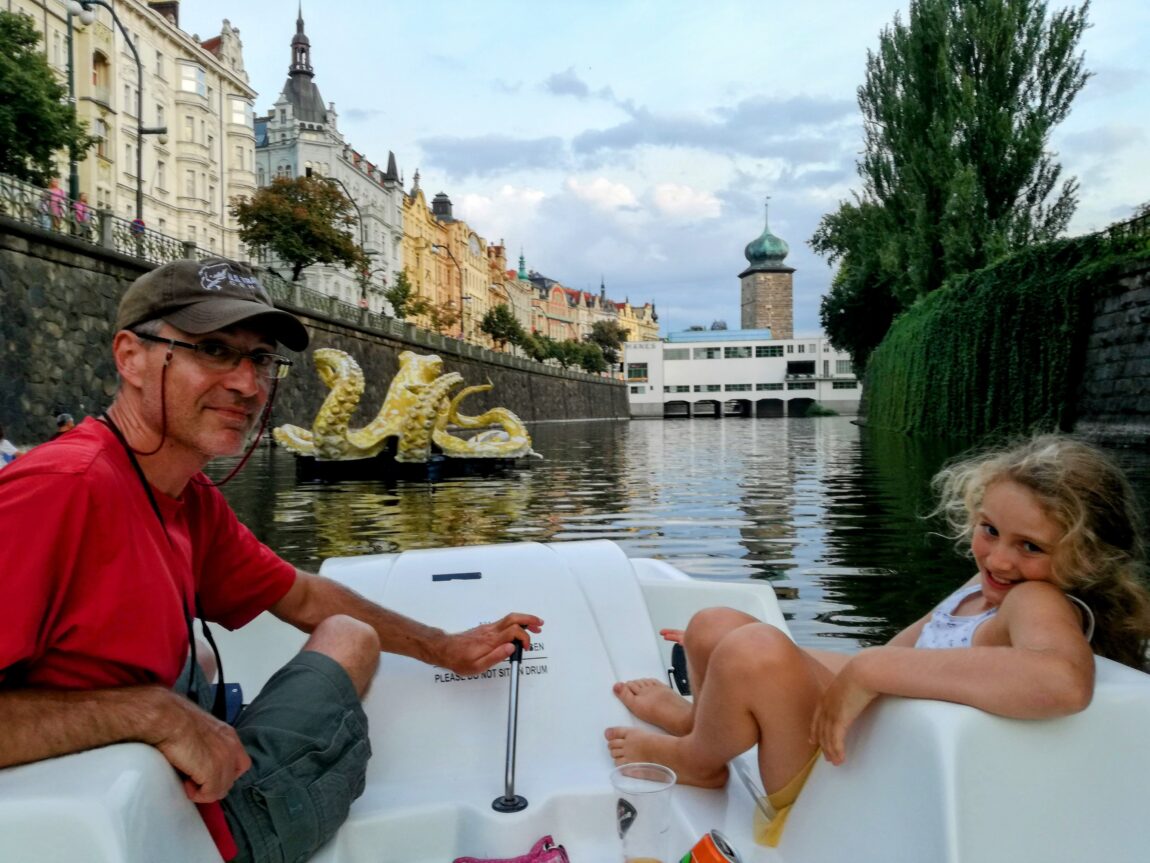 A father and daughter sitting in a paddle boat on the Vltava River in Prague on a sunny summerday.