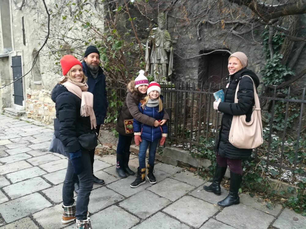 Four adults and one child standing in front of an old building in Vienna, smiling while looking at the camera