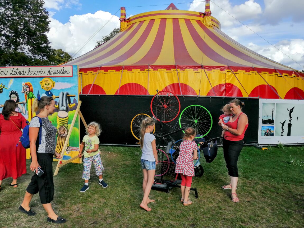 Children looking at bicycle wheels in front of a circus tent set up in Letna Park, Prague, for Letni Letna Festival