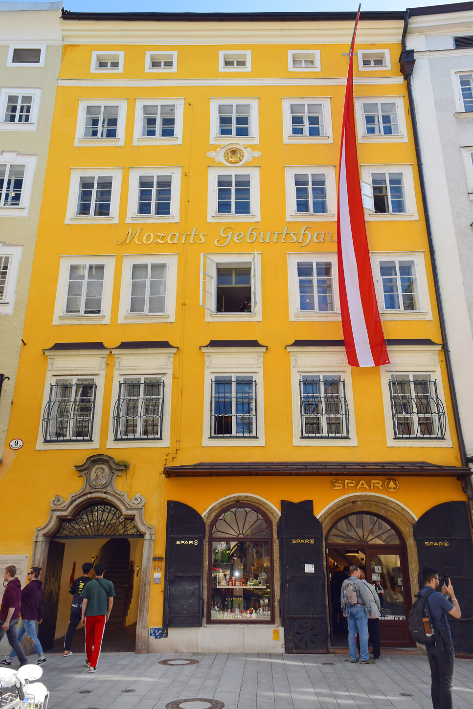 Tourists standing in front of a bright yellow building, Wolfgang Amadeus Mozart's birthplace house