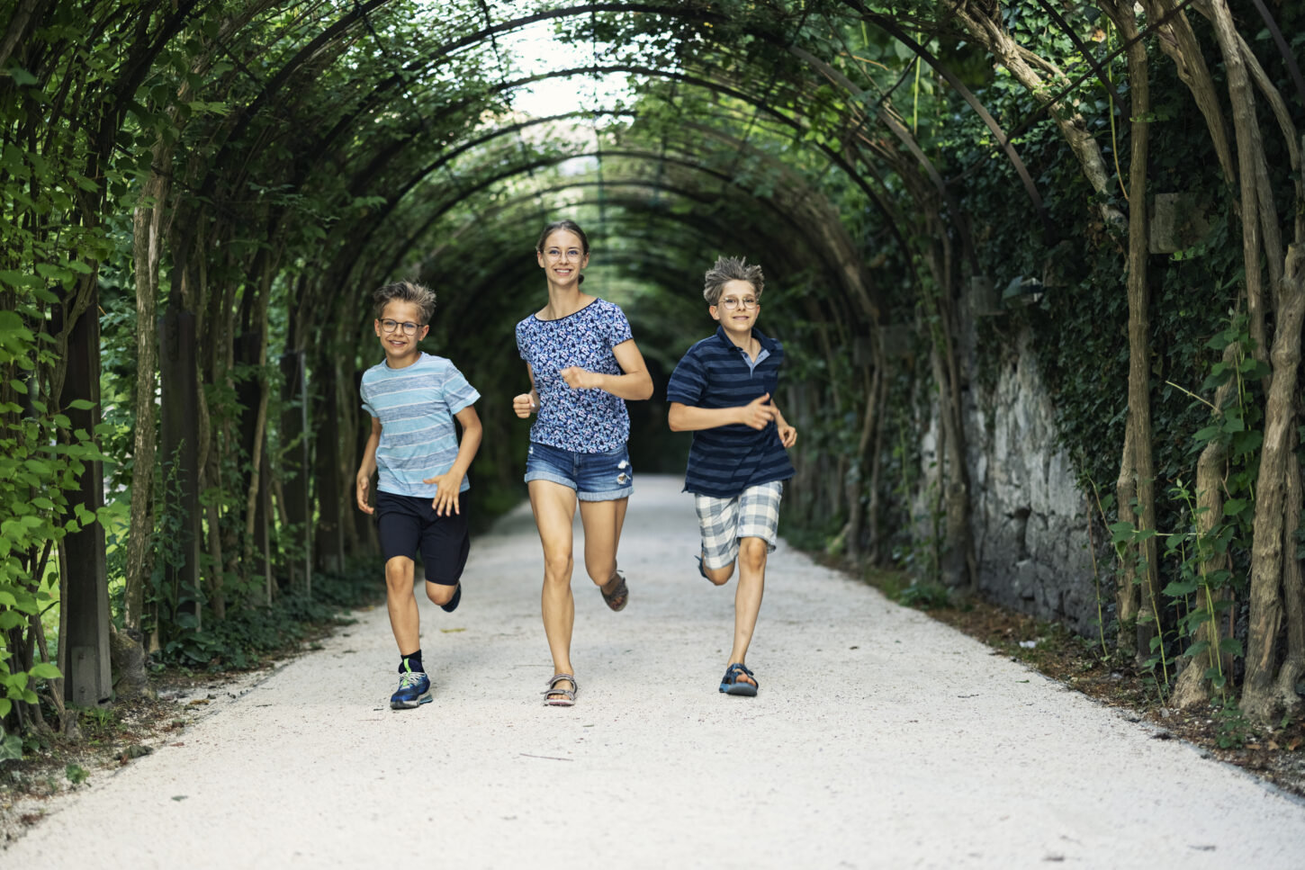 Three kids are running in the vin tunnel at the park Mirabell Gardens in Salzburg.
