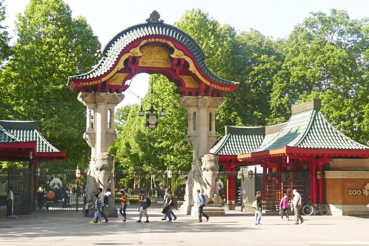 Entrance to Berlin Zoo, with a red archway and leafy green trees