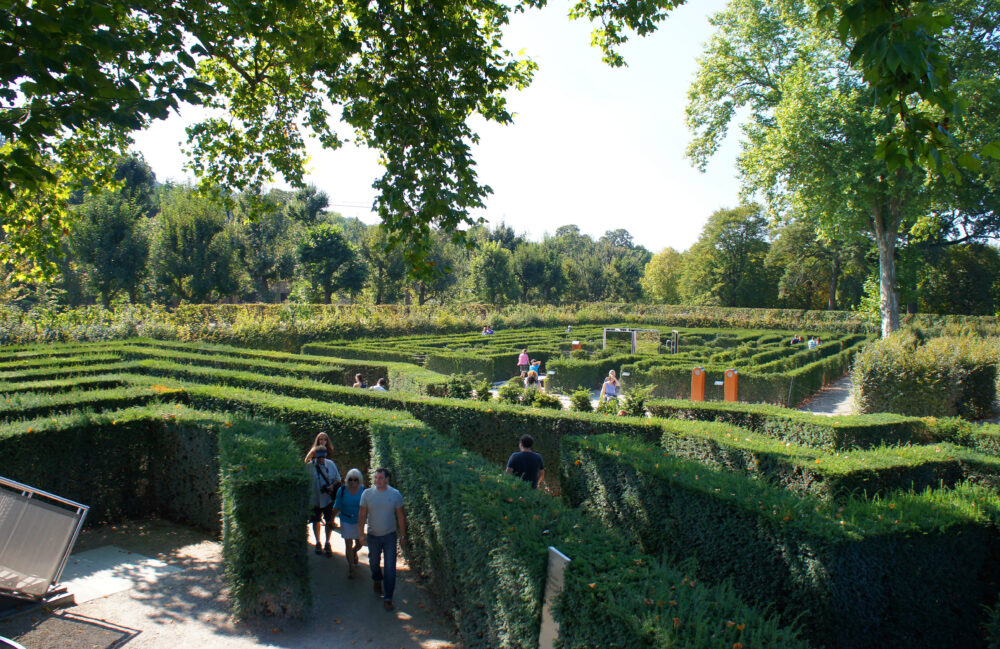 Tourists walk among the hedge maze in Schoenbrunn Palace Park Vienna in sunny day.