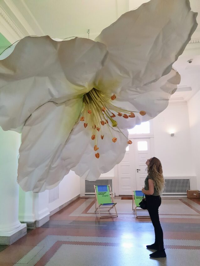 A young women is looking at a giant flower at an art exhibition in Berlin, Germany