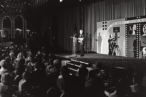 A black-and-white photo showing a man accepting an award on stage at a Film Society convention in 1979