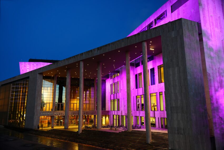 Image of the Museum Ludwig building in Budapest, Hungary, at night, with purple lights.