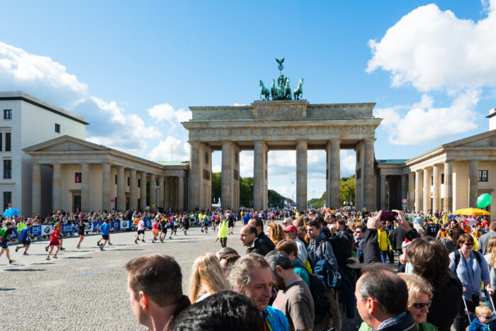 A crowd looks on as Berlin marathon runners reach the finish at Brandenburg Gate in Berlin, Germany.