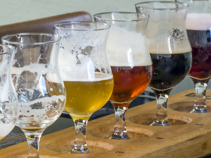 Different types of beer in tasting glasses on a wooden bar