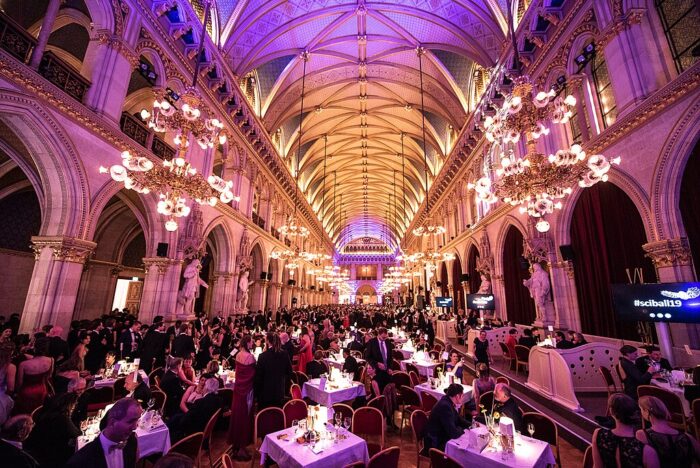 A grand hall in Vienna, Austria, with several tables and people dressed up for a ball