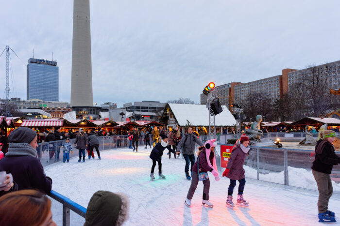 Kids skating at a rink on a cold gray day at a Christmas Market in Town Hall in Winter Berlin, Germany.