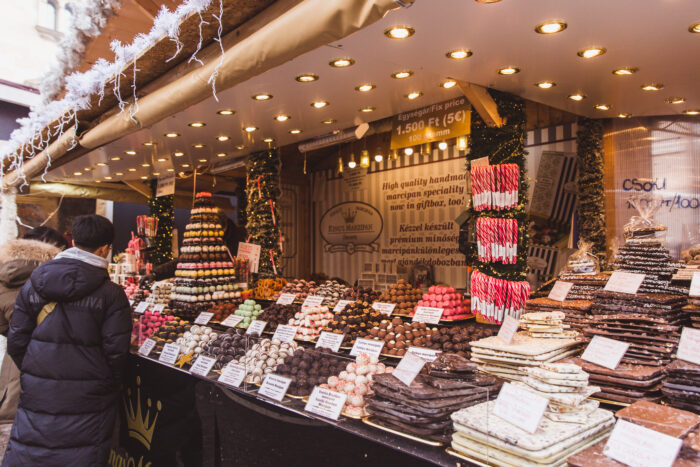 A market stand in a Christmas market at St. Stephen's Basilica, Budapest, with customers looking at various sweets