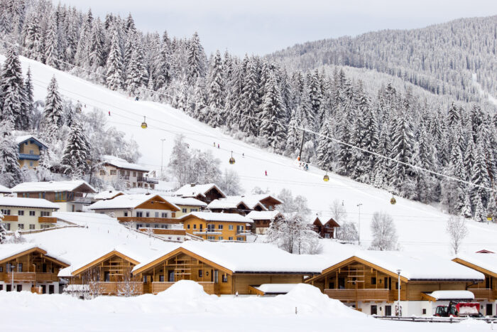 Ski slope at Flachau, Austria, covered in snow, with some builings in the foreground and a ski lift in the background. 