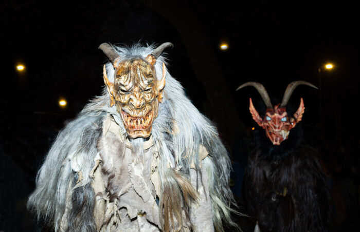 Two people in devilish Krampus costumes at a nighttime Krampus run in Salzburg, Austria