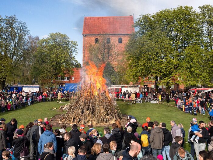 A crowd of people standing around a giant bonfire at Easter in Berlin, Germany