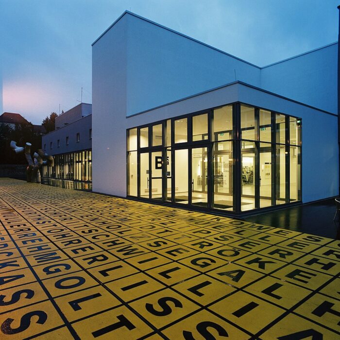 Entrance to the Berlinische Gelerie in Berlin at dusk, with yellow light shining out of the windows.