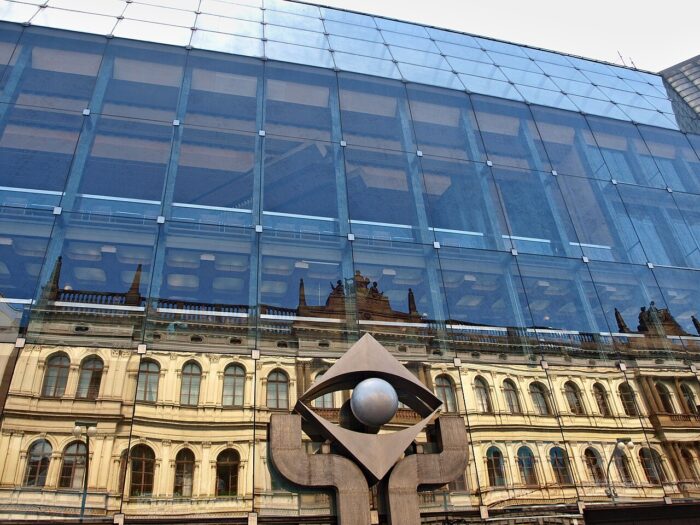 The glass facade of teNew Sage building at National theatre Prague, with the building across the street reflected