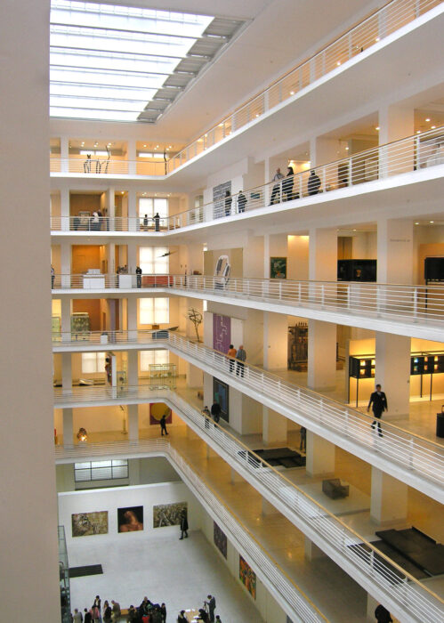 Atrium of Prague National Gallery: Trade Fair Palace, with many floors in a white building and a skylight