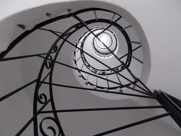 a white spiral staircase with black metal railings in Budapest, Hungary