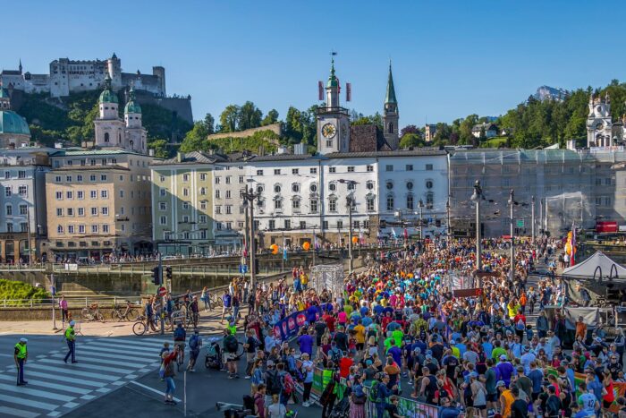 A large group of people running past a historic building during the Salzburg Marathon in Austria