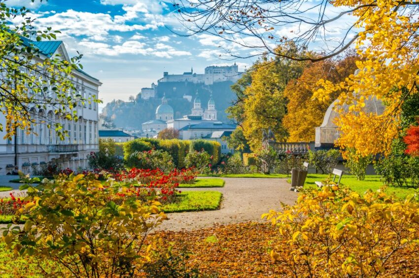View of Hohensalzburg Fortress from Mirabell Gardens in Salzburg, Austria, with trees and bushes bright yellow and red in autumn color