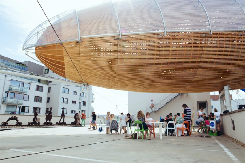 Visitors sitting beneath the large suspended Zeppelin sculpture inside DOX Centre for Contemporary Art in Prague.